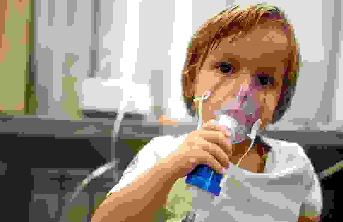 Young child holding breathing apparatus over nose and mouth
