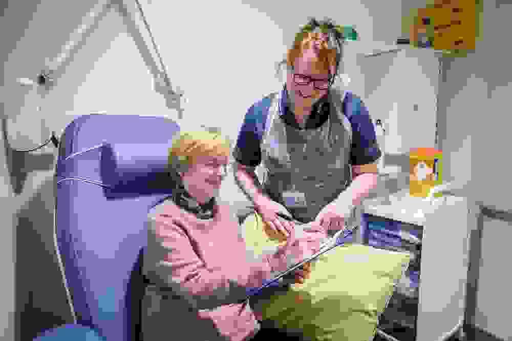 Volunteer in purple jumper signing form with a member of the clinical team watching